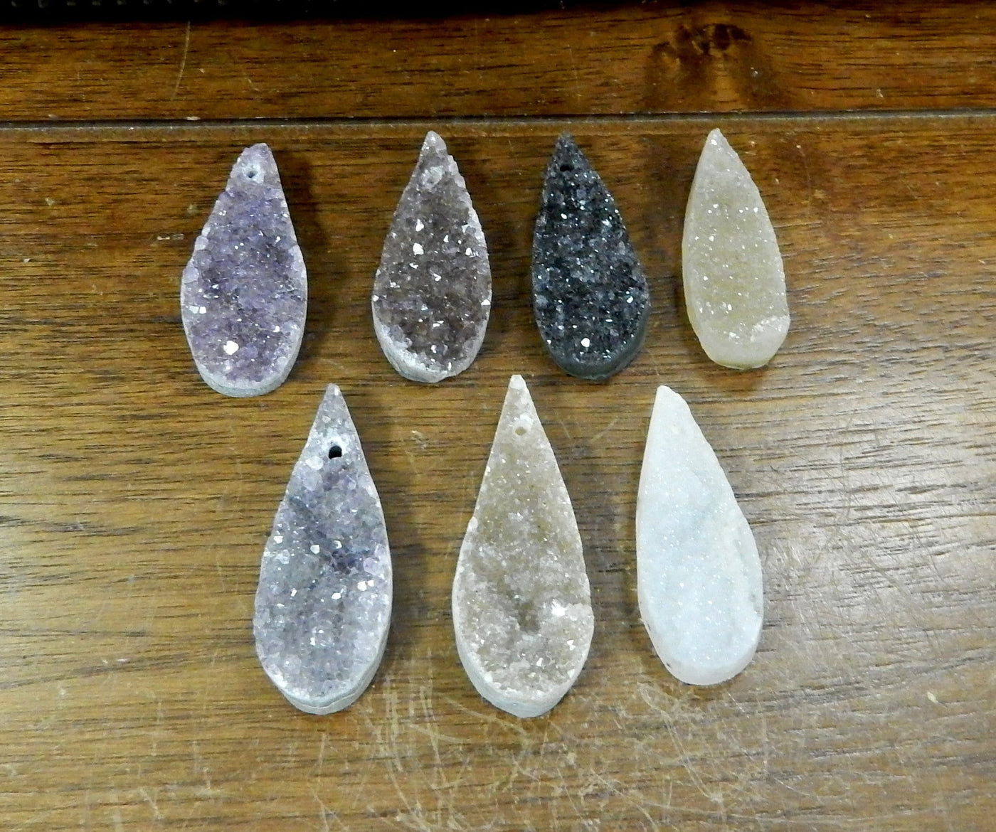 7 Druzy Teardrop Top Center Drilled Beads laid out to show color variety