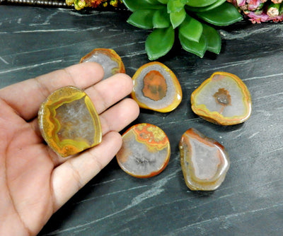 Hand holding up Red Chinese Agate Cabochon with others in the background