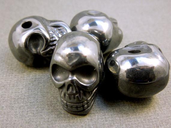 many grey hematite skull beads in a pile for possible variations 