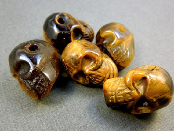 many tiger eye skull beads in a pile for possible variations