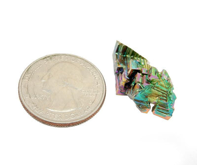 bismuth crystal next to a quarter showing the size