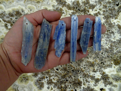 Blue Kyanite Blades with drill on top in a hand for size reference