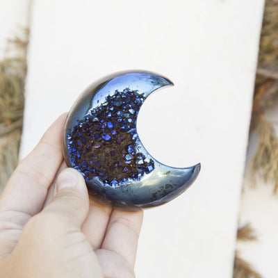 One Agate Druzy Moon in a hand with a white background.