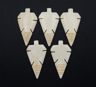 5 Carved Bone Arrowhead Top Side Drilled Beads on black background
