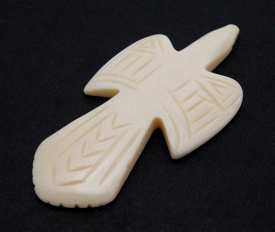side angle close up of one carved bone cross on a black background