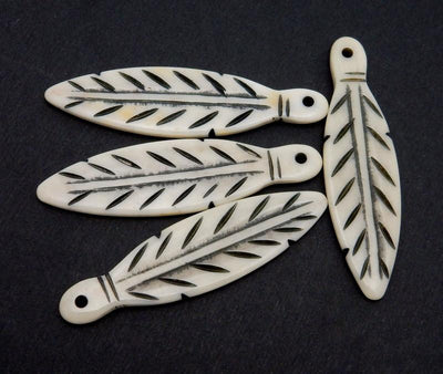 4 carved bone feathers on a black background