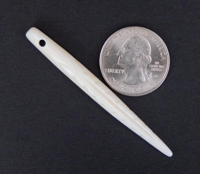 bone spike bead next to a quarter for size reference