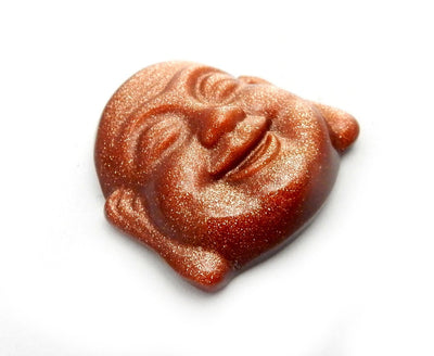 angled shot of Goldstone Buddha Head Cabochon on white background