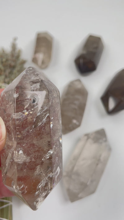 video of one large drilled smokey quartz double terminated point in hand and then close ups of many others on white background