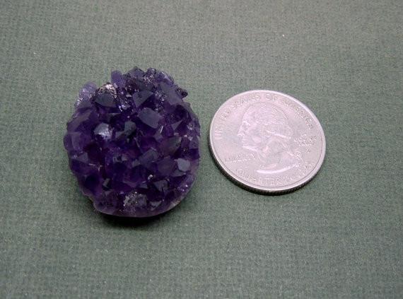A Flat Back Amethyst Cluster next to a quarter.