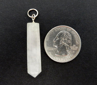  a single Calcite Crystal Point Pendant with Silver tone Bail next to a quarter on a black background