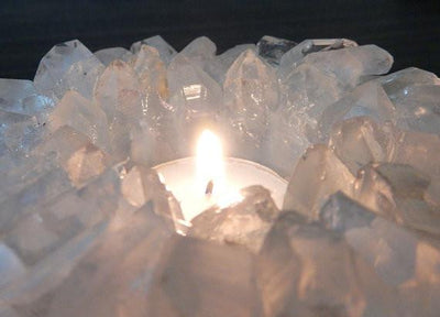 up close shot of crystal quartz point candle holder with a candle lit in it