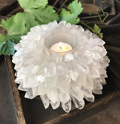 Crystal candle holder that has crystal points glued throughout on a wood background.