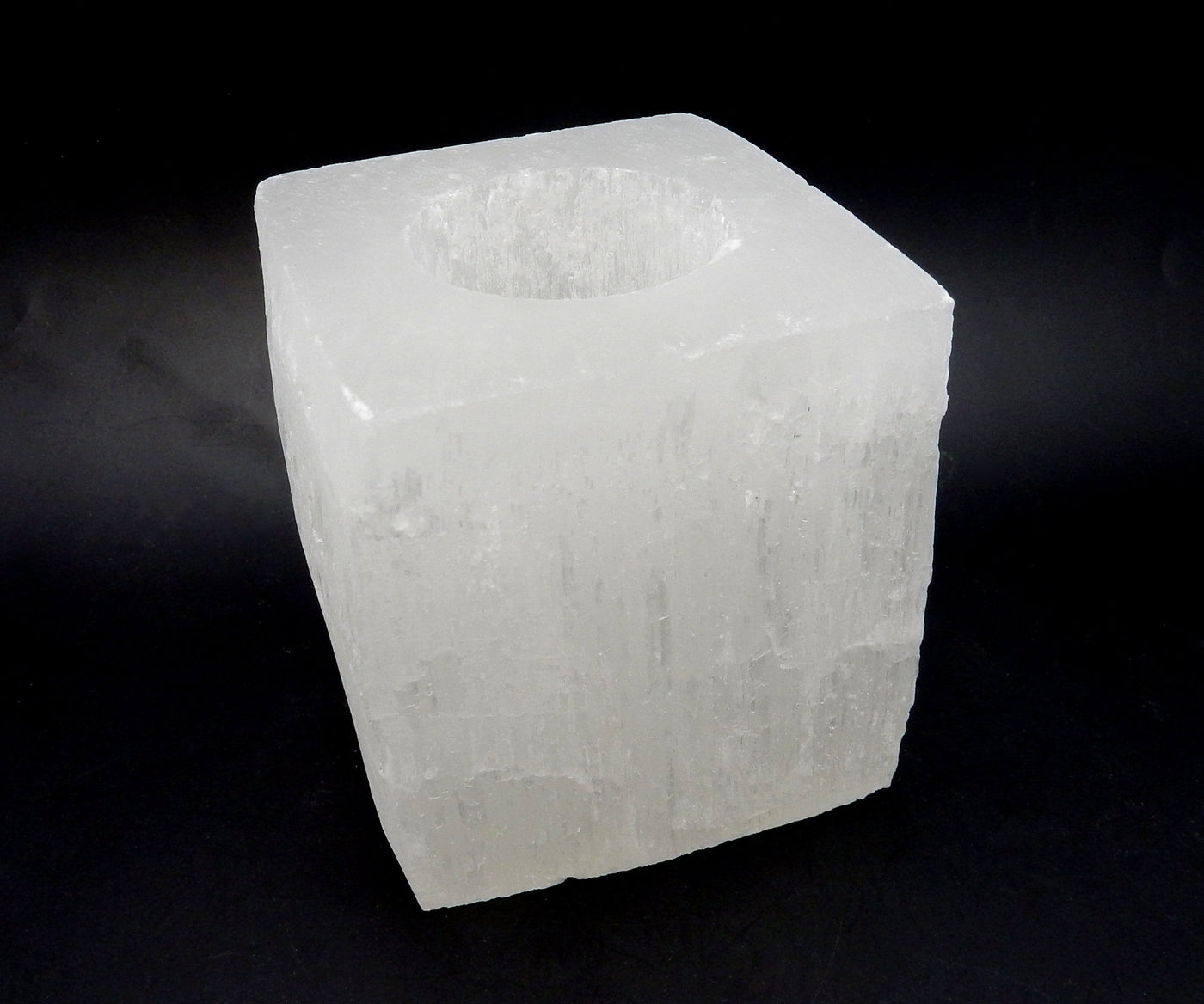 Close up of a single Square Shaped Selenite Candle Holder  on a black background