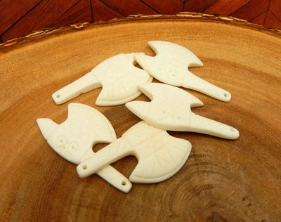 5 carved bone axe heads sitting on a wood background