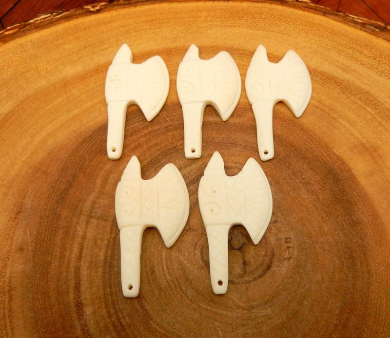 5 carved bone head axes facing right on a wood background