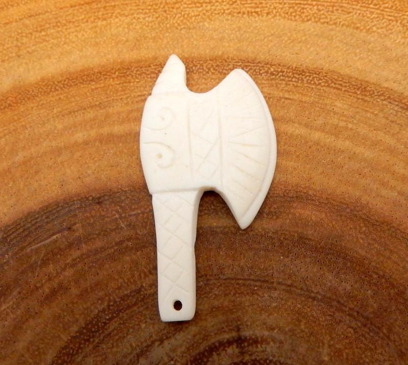 close up of one bone carved head axes on a wood background