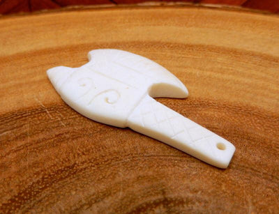 side angle close up of carved bone axe head on a wood background