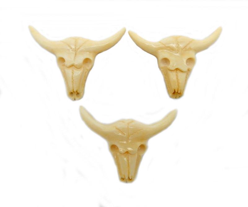 3 carved bone cattle skulls on a white background