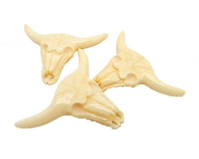 3 carved cattle bone heads stacked on top of each other with a white background