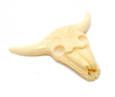 side angle close up of one carved bone cattle head on a white background