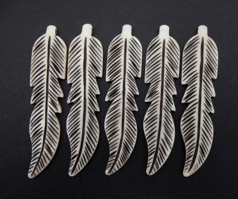 5 carved bone feathers on a black background