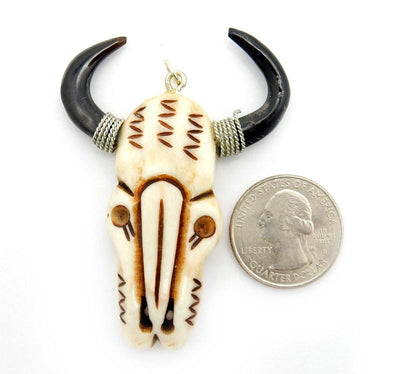 one bone carved cattle head next to a quarter on a white background