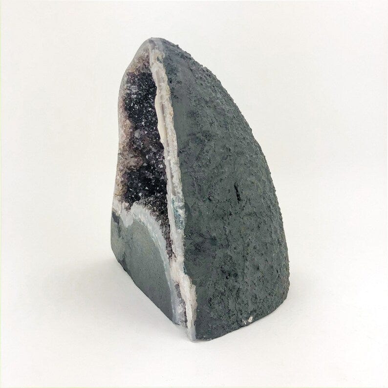 Side view of the amethyst geode on a white background, showing the back is painted black.