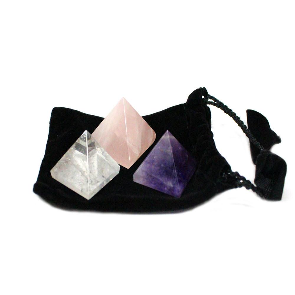 Crystal quartz, rose quartz, and amethyst pyramids on a black velvet bag.