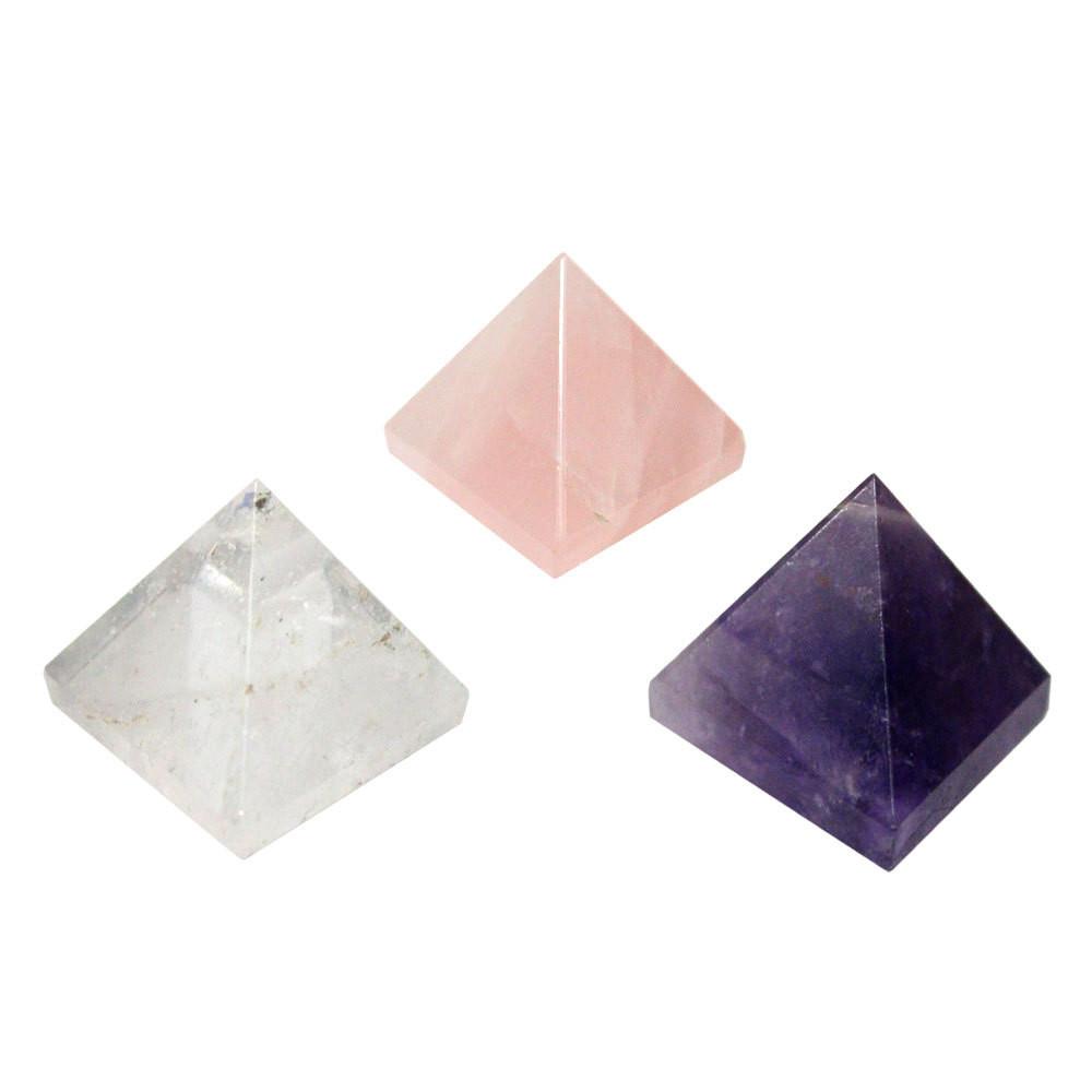 Crystal quartz, rose quartz, and amethyst pyramids on a white background.