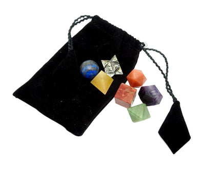 Seven chakra sacred stone geometry set with a black velvet pouch on a white background.