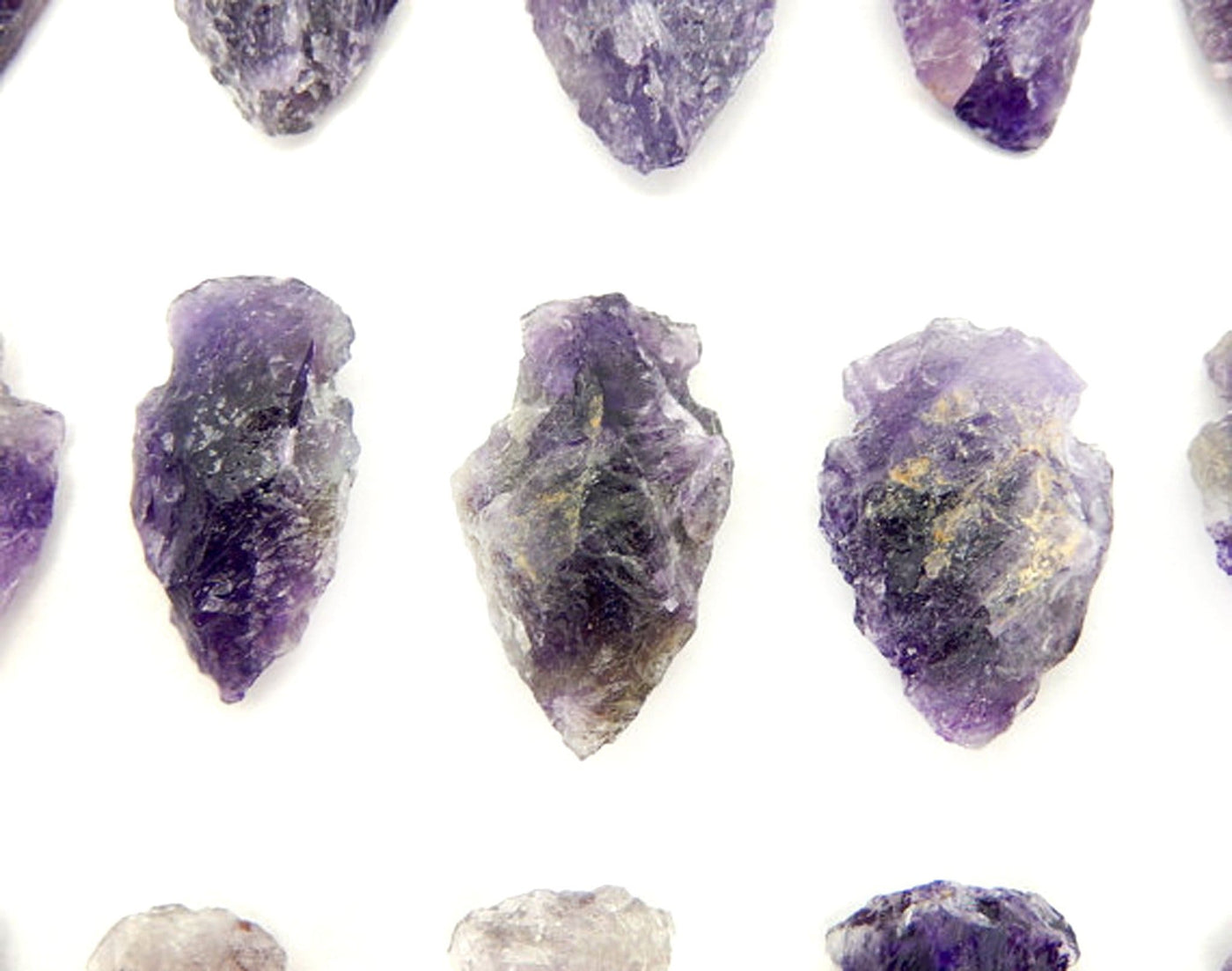 Picture of  3 amethyst arrowheads displayed on a white back ground for size reference.