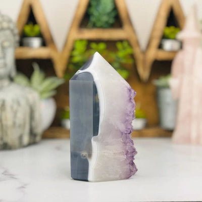 side view of Amethyst Druzy Polished Tower Point with decorations in the background