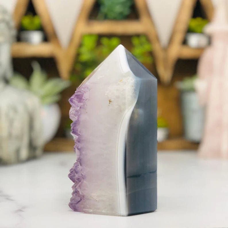 side view of Amethyst Druzy Polished Tower Point with decorations in the background