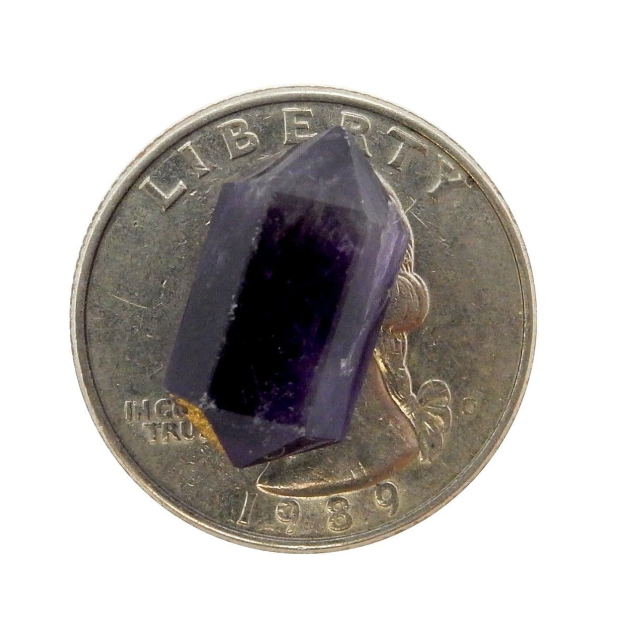 Petite Amethyst Double Terminated Pencil Point on top of a quarter for size comparison