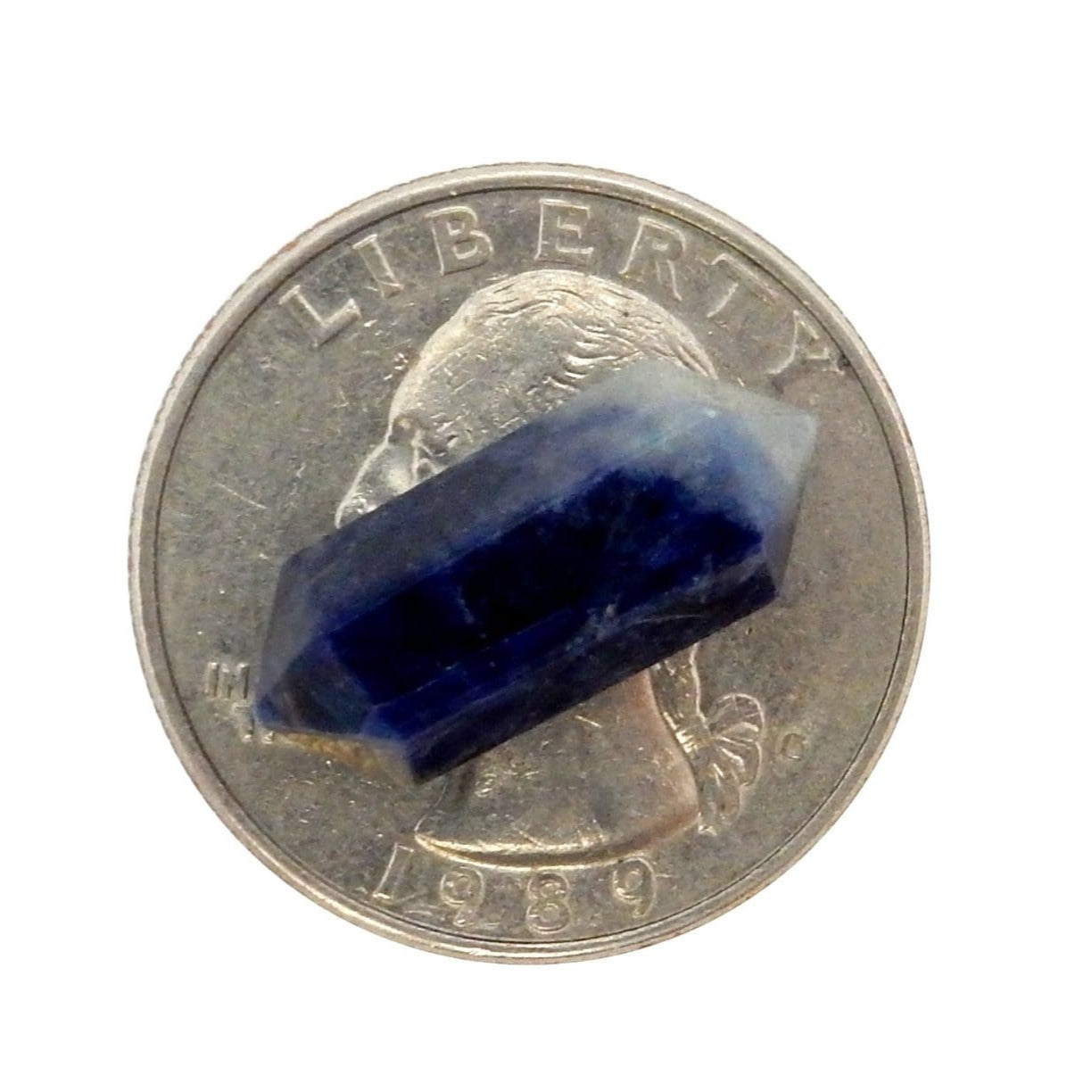 Single Petite Sodalite Double Terminated Pencil Point on top of a quarter for size comparison