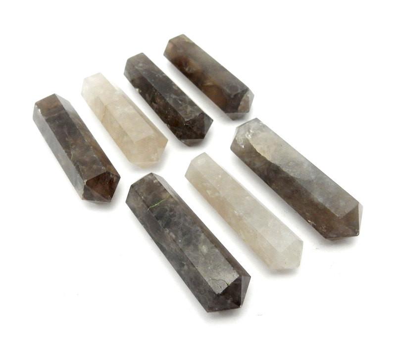 angled view of seven smokey quartz double terminated pencil points in two rows on white background for approximate thickness
