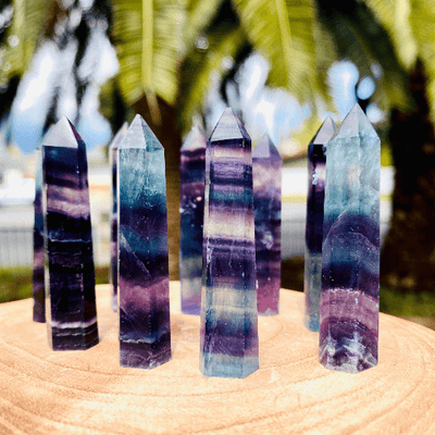 4 up close Rainbow Fluorite Polished Points on wood display with 4 others blurred behind 