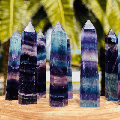 Up close shot of 3 Rainbow Fluorite Polished Points with 4 standing behind them