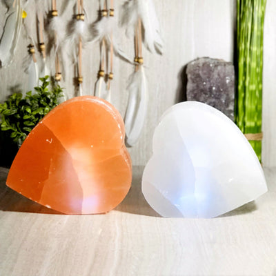 orange and white selenite heart shaped lamps lit up in natural light