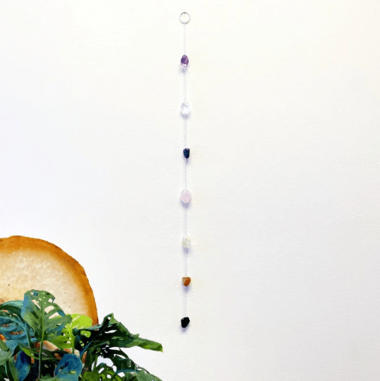 tumbled stone chakra wall hanging with silver chain hanging on a wall
