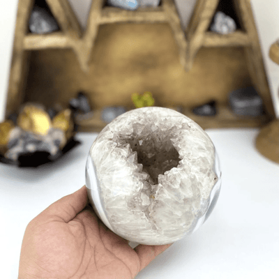 amethyst sphere on a white background.  It is mostly white with an open druzy center containing light amethyst.