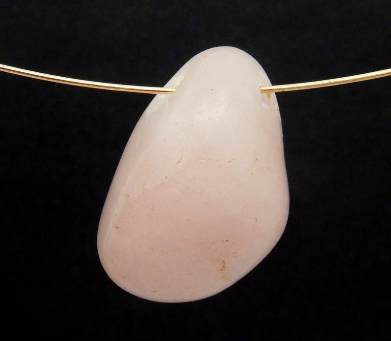 Drilled Tumbled Stone Rose Quartz Beads With Wire Shown as a Necklace on Black Background.