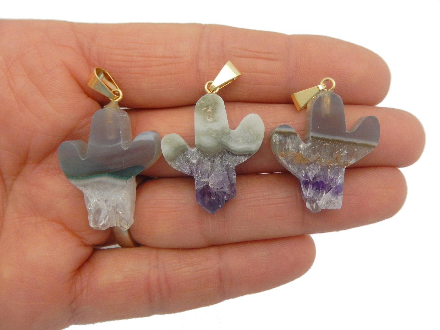 hand holding up 3 amethyst slice cactus pendants for size reference