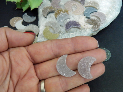 hand holding up 2 Druzy Moon Cabochons with others in the background