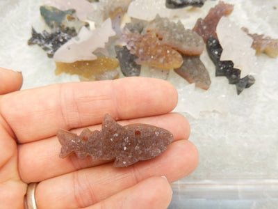 Hand holding a Nautal color Druzy Shark Fish Cluster Cabachon for size reference 