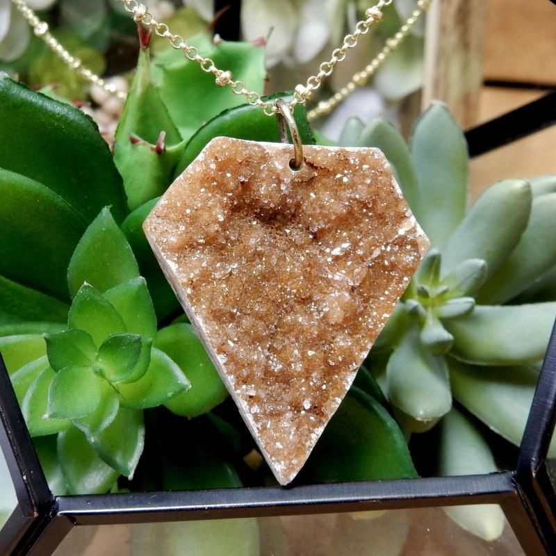 Diamond Shaped Druzy Cabochon Hanging in Necklace on Succulent Background.