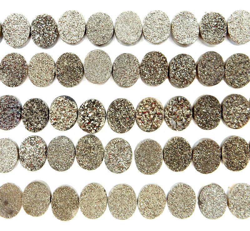 druzy cabochons lined up in rows on white background