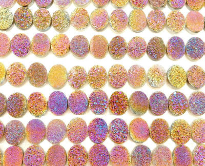 multiple purple and yellow oval cabochons displayed to show the differences in the color shades 