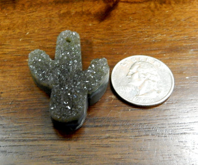 One druzy quartz cut into a cactus shape with a drill hole on top placed next to a quarter.  It is slightly larger than the quarter.